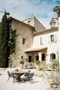Terrasse ensoleillée des Domaines de Patras, mas en pierre typique de Provence avec salon extérieur et ambiance élégante.